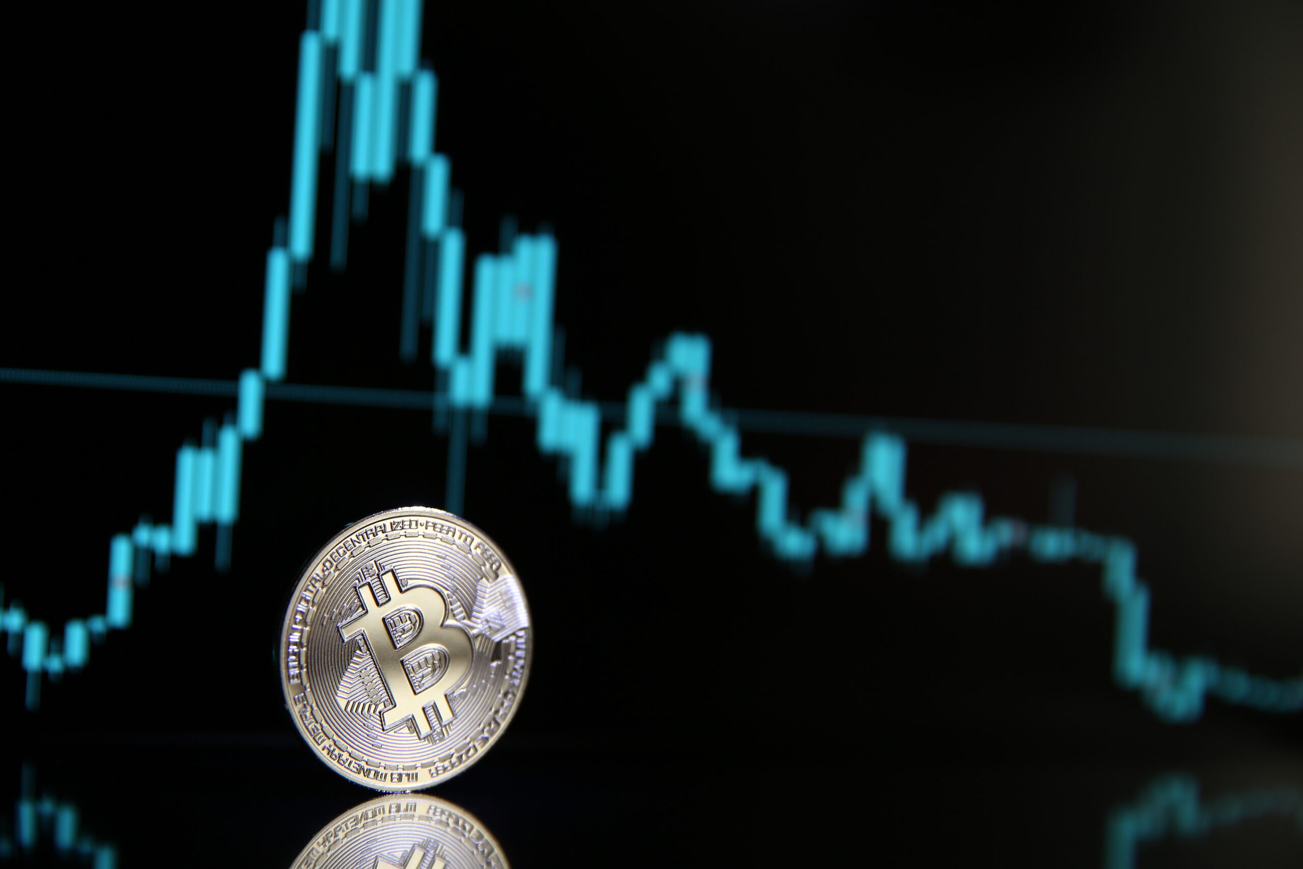 A physical Bitcoin coin in the foreground with a glowing digital price chart in the background, representing market momentum and trading activity related to a potential breakout.