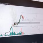 Monitor displaying candlestick chart with green and red trend lines, signaling potential breakout in cryptocurrency market.