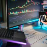 Person analyzing crypto charts on multiple monitors with Bitcoin and Ethereum price drops visible.