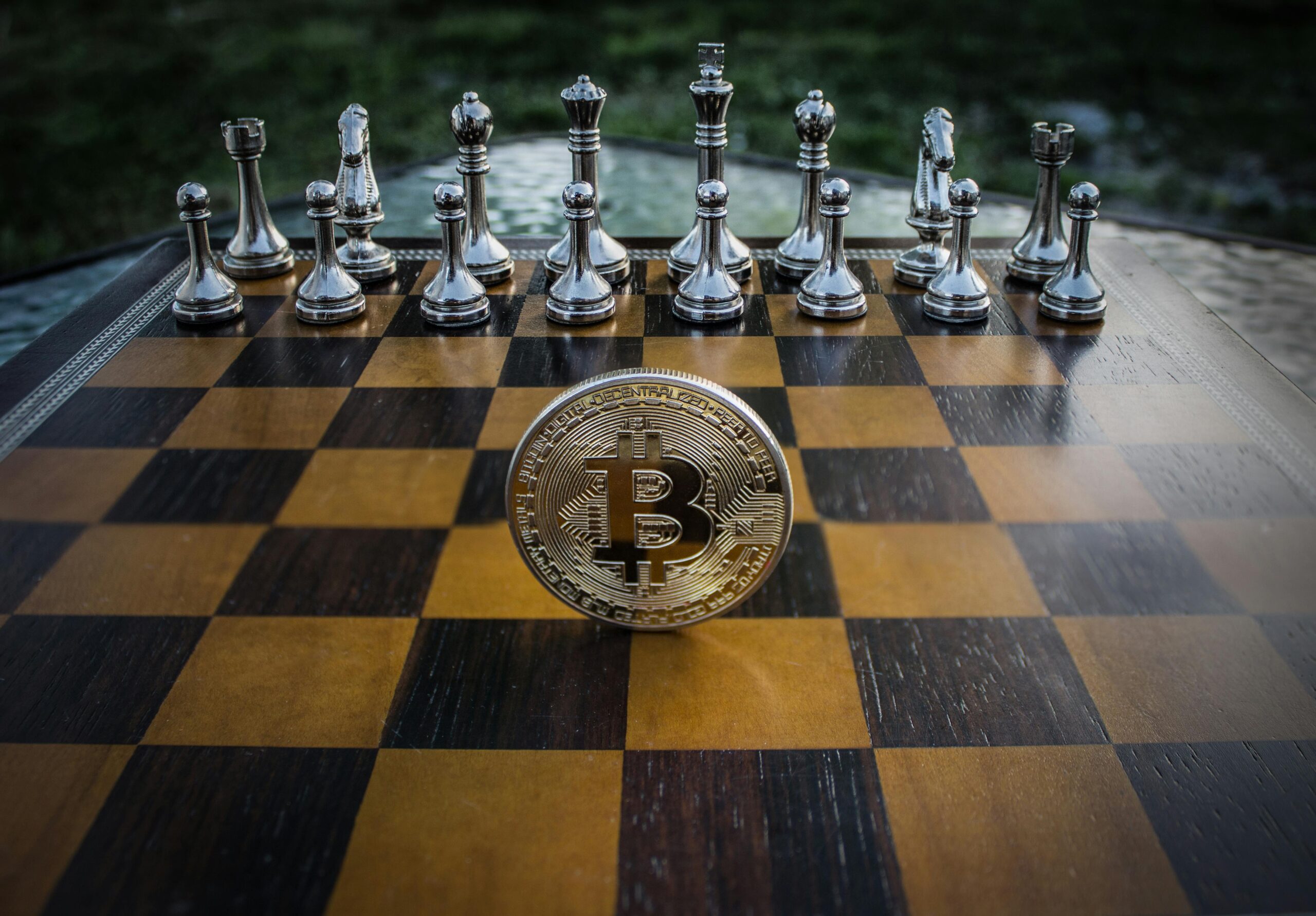 Chessboard with Bitcoin coin among glass pieces, symbolizing strategic investment moves in crypto.